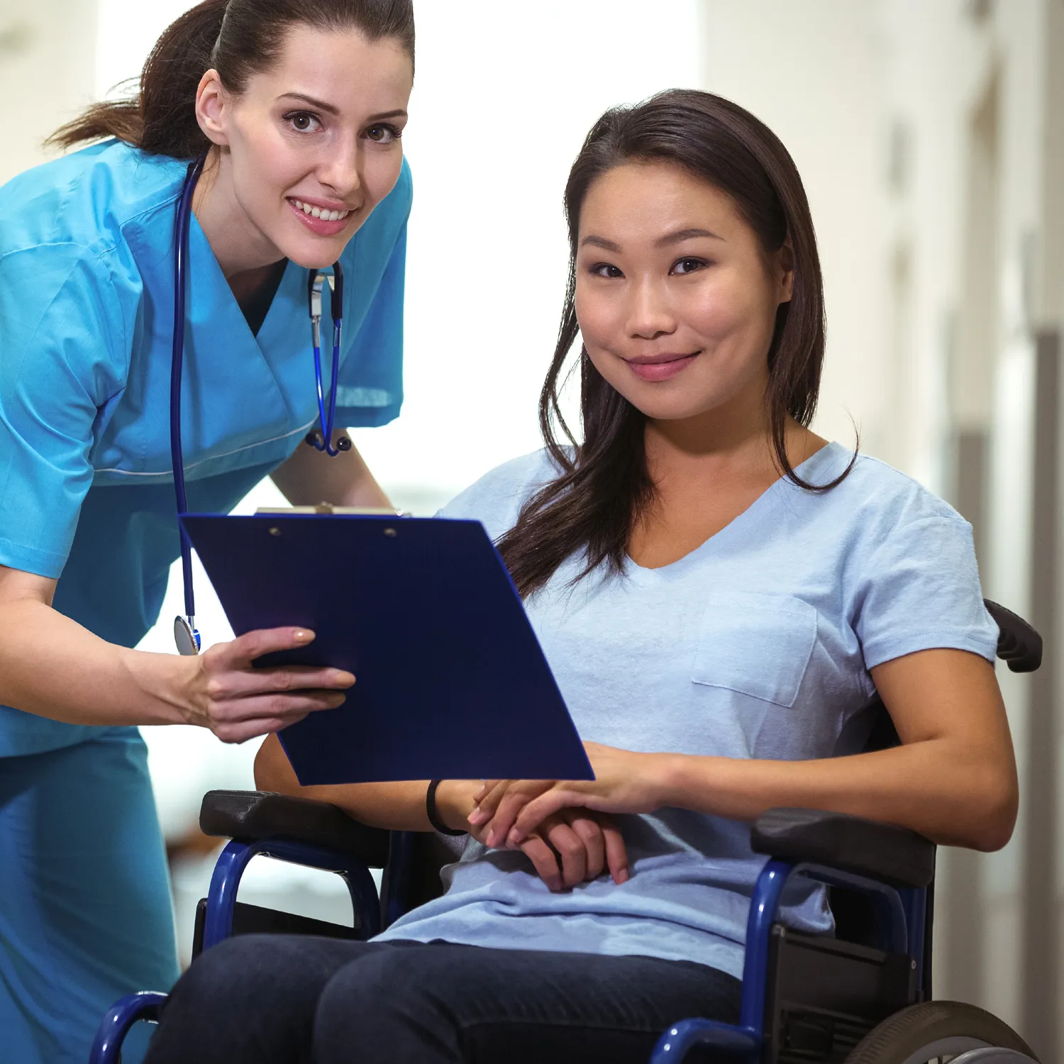 Community Nursing Care 3 Community nurse reviewing notes with a participant in a wheelchair